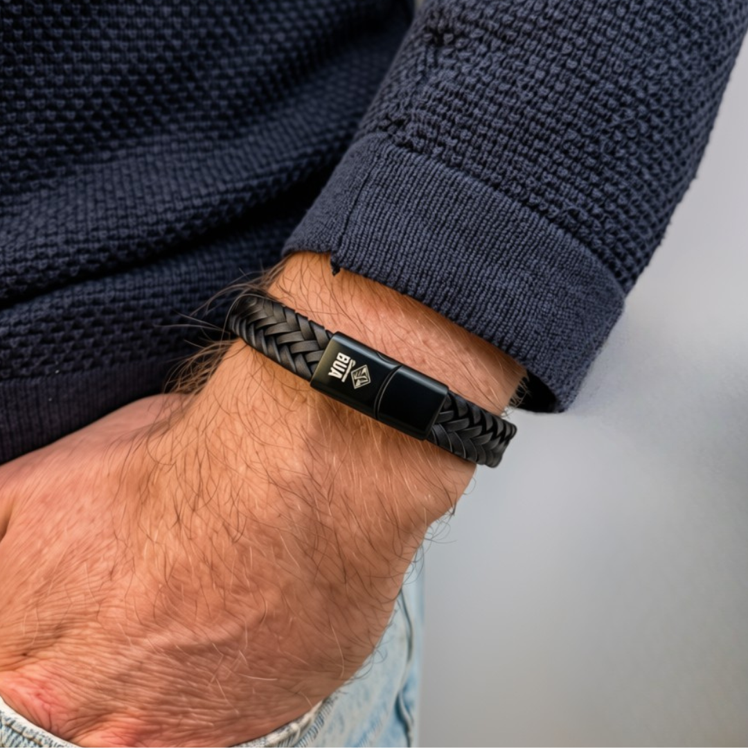 Bavarian BUA Armband Flecht in Schwarz, breit geflochten, am Handgelenk zu dunkelblauem Strickpullover.