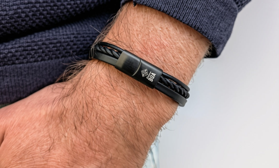Schwarzes Lederarmband Trio mit drei Strängen und mattschwarzem Verschluss am Handgelenk.
