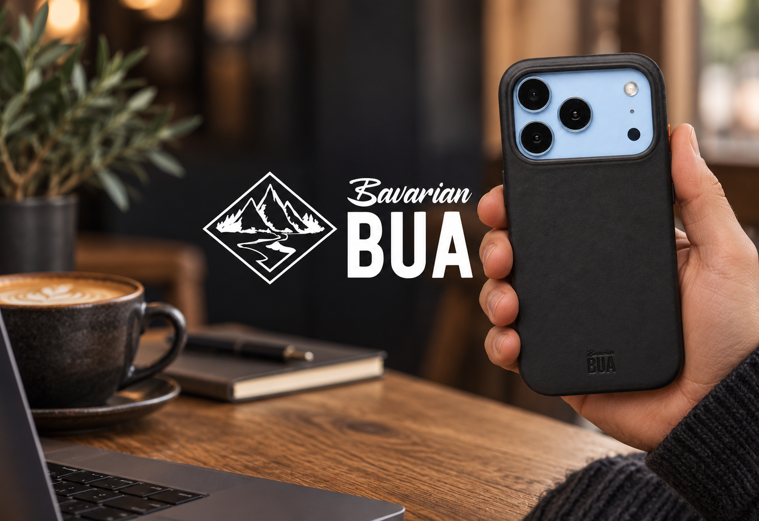 Schwarze Lederhülle in der Hand im Café mit weißem Bavarian-BUA-Logo – gestaltetes Anwendungsmotiv