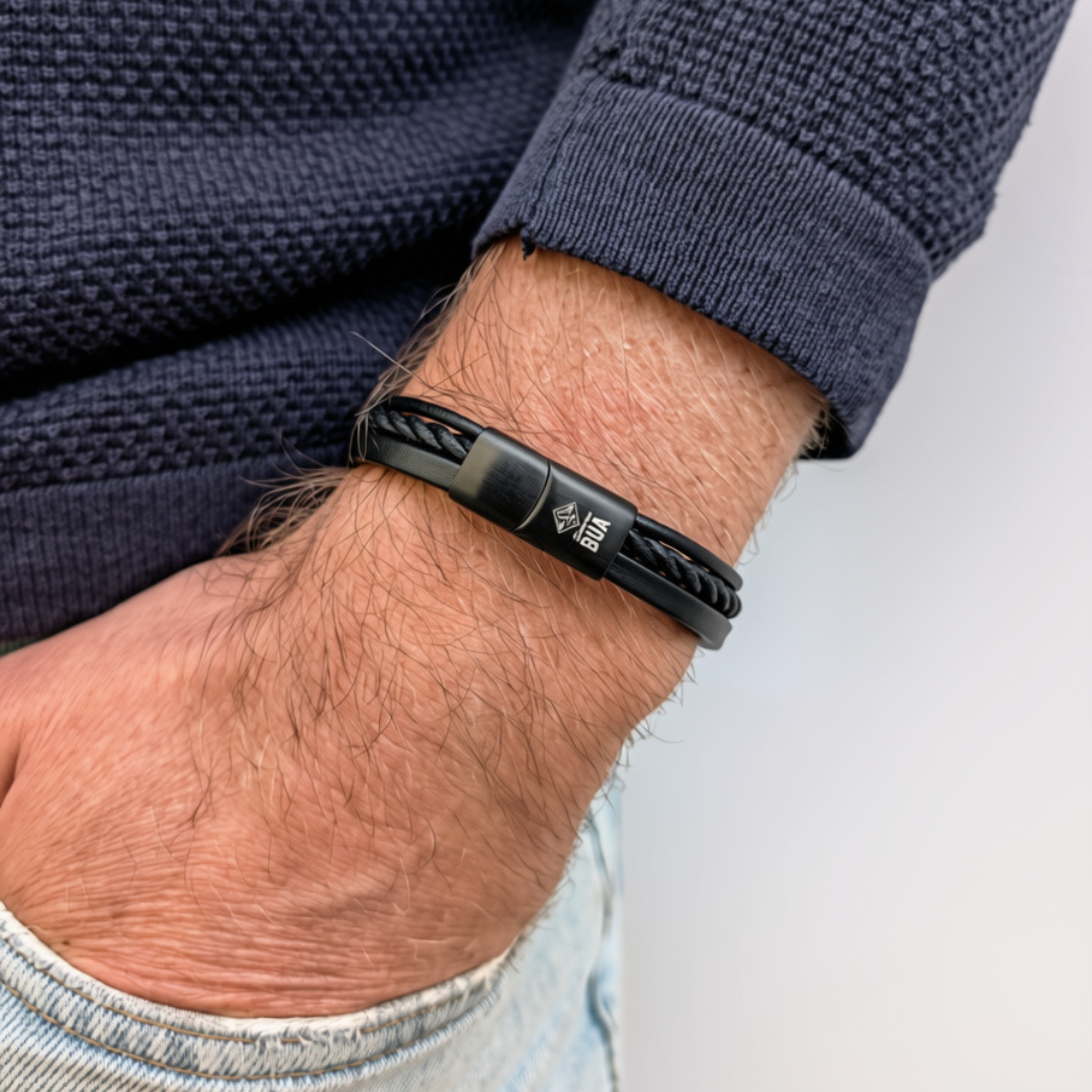 Bavarian BUA Armband Trio in Schwarz, mit drei Strängen aus Leder und Textil, am Handgelenk zu dunkelblauem Strickpullover.