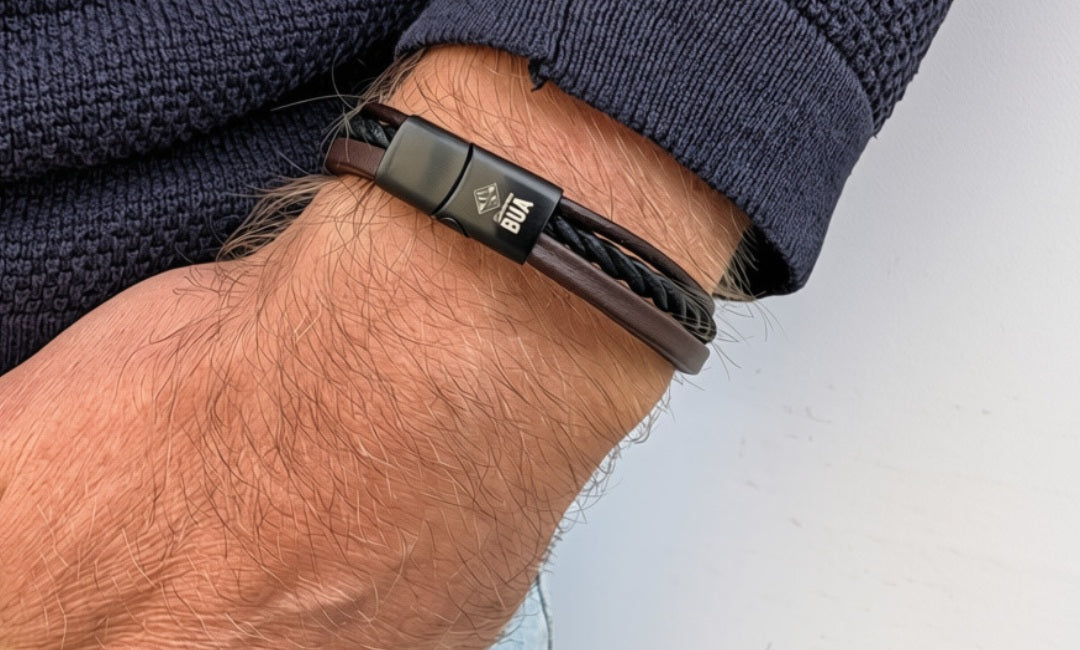 Lederarmband Trio in Braun-Schwarz mit drei Strängen am Handgelenk zu dunkelblauem Strick.